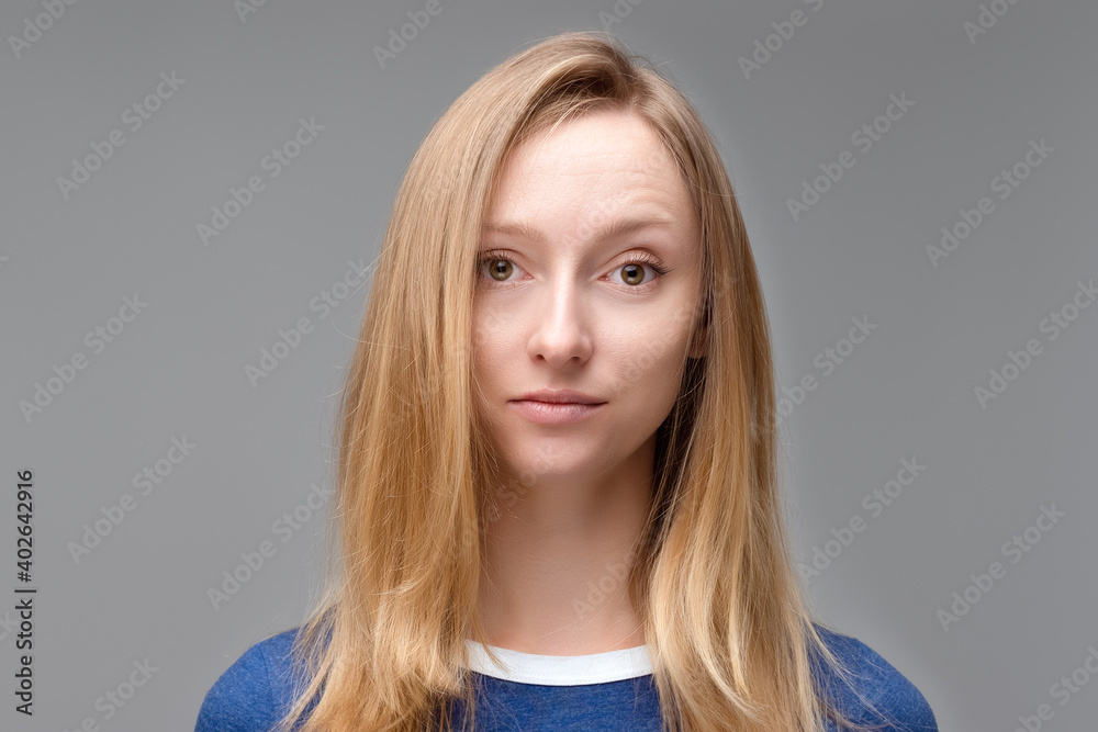 Fototapeta premium Close up Portrait of young beautiful woman with blond hair and in blue T shirt look at camera, posing in studio, isolated on grey studio background