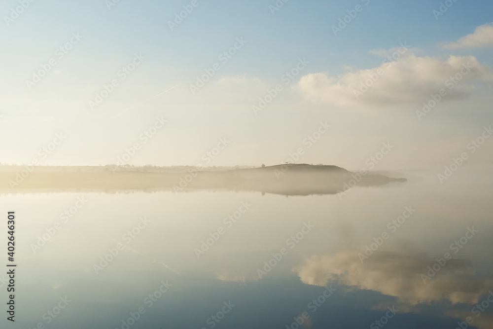 mist laying over the calm water on a silent morning at Flyndersoe lake in Denmark