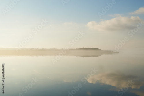 mist laying over the calm water on a silent morning at Flyndersoe lake in Denmark