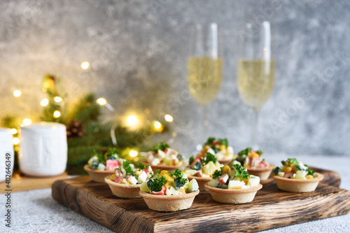 Tartlets with crab sticks and corn and champagne in a glass on the New Year's table.