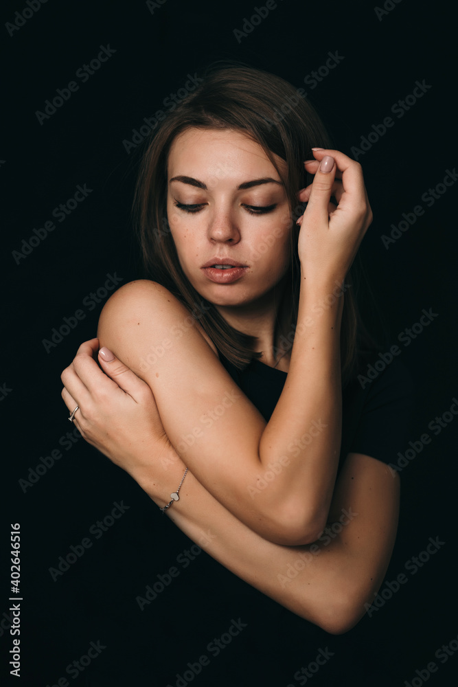 Serious girl on a black background. Beautiful girl in black on a dark background. The girl thinks about her problem
