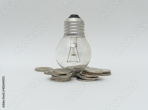 Isolated Bulb with coins. Money spent with light bulbs. Concept of energy efficiency