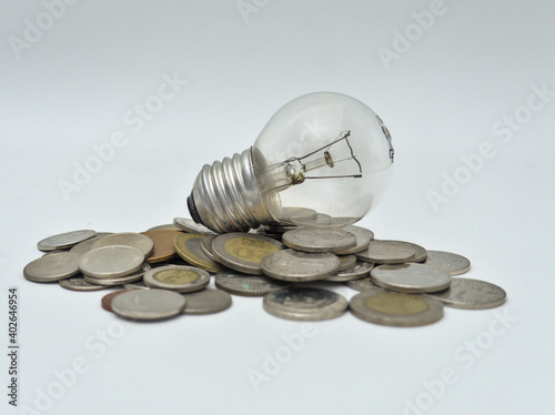 Isolated Bulb with coins. Money spent with light bulbs. Concept of energy efficiency