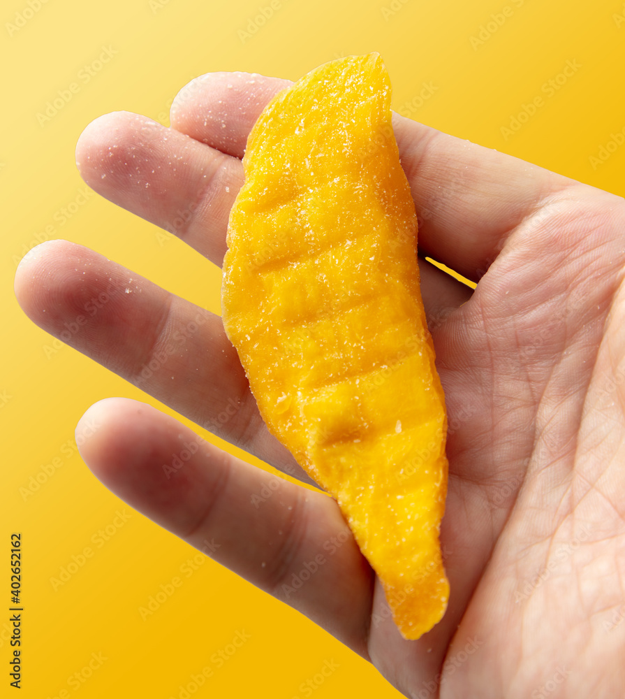 Dried mango in hand isolated on yellow background. Dried mango in hand isolated on yellow background.