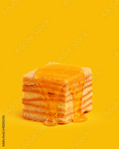 fresh honey flows through the appetizing cake. image on a yellow background.