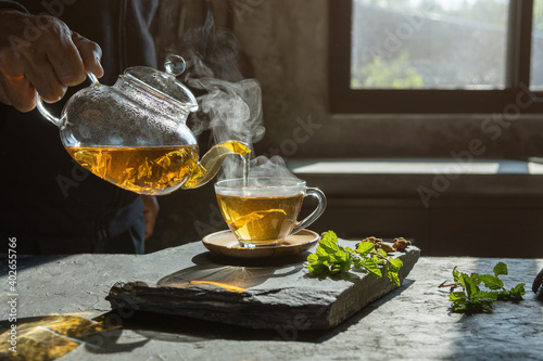 Cup of hot tea  dry tea leaves with steam and mint herb.