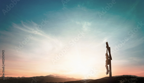 Silhouette Jesus Christ on holy cross against mountain sunset background