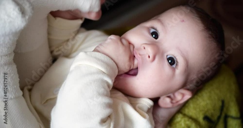 happy Little baby boy playing with his legson mother hands. Bite and suck his foot toes. 4K photo