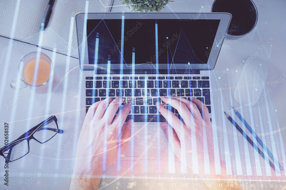 Double exposure of man's hands typing over laptop keyboard and forex chart hologram drawing. Top view. Financial markets concept. Double exposure of man's hands typing over laptop keyboard and forex chart hologram drawing. Top view. Financial markets concept.