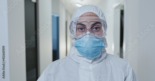 Nurse or doctor wearing face mask and goggles dressed n full protective clothing during the Covid-19 coronavirus pandemic standing in a hospital corridor.