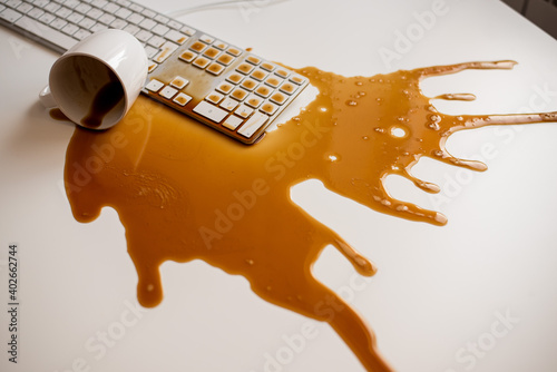 Fotografía Spilled black coffee on a computer keyboard at a white table