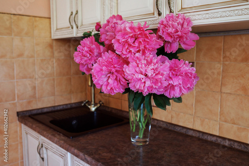 Fototapeta Naklejka Na Ścianę i Meble -  Beautiful peonies bouquet is in vase in the kithcen. Summertime flowers.