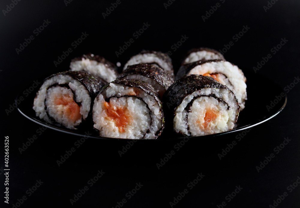 chopstick holding a sushi roll on a black background chopstick holding a sushi roll on a black background