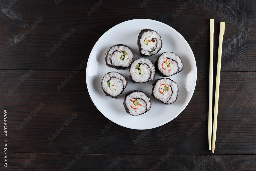 Set of fresh a sushi rolls in a white plate on a wooden table, top view