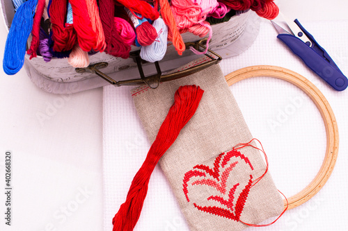 A pouch with embroidery lies next to a box of threads, top view