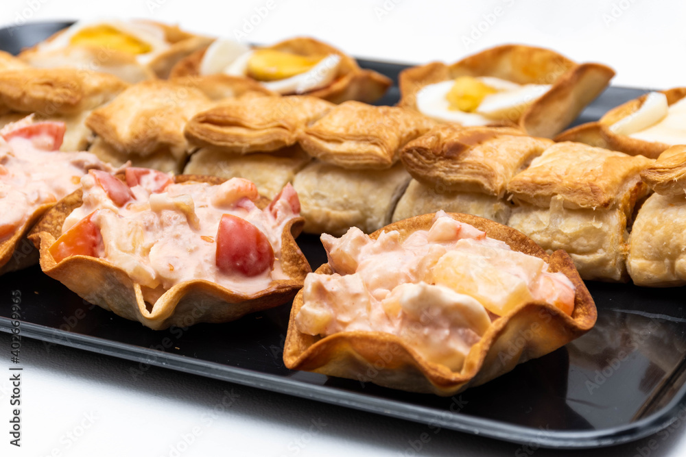 Horizontal black tray with an assortment of lids and salted canapés on a white background. Horizontal black tray with an assortment of lids and salted canapés on a white background.