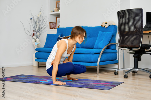 woman doing yoga arm balance exercise with crossed legs