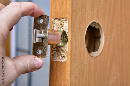 Locksmith shoves the latch Into hole of interior door.
