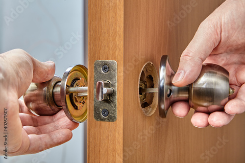 Carpenter inserts one half of the doorknob In through the latch.