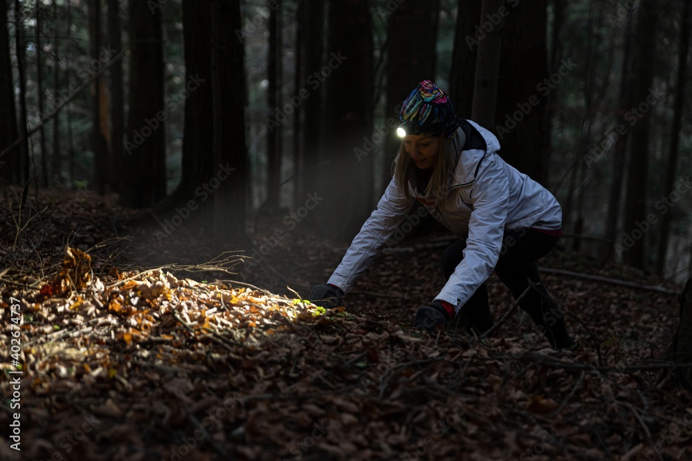 Beauty tourist woman with headlight in the forest at dark
