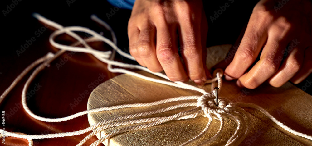 Obraz premium First knots to make a macrame coaster from a rope on a plate of wood