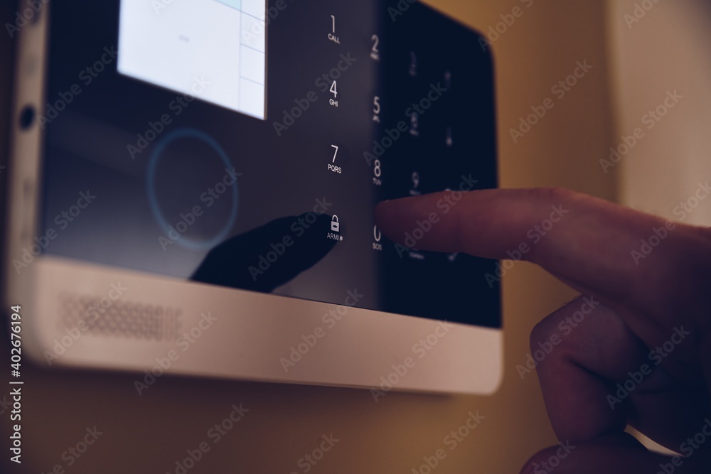 Man arming home security alarm. Home alarm system control panel