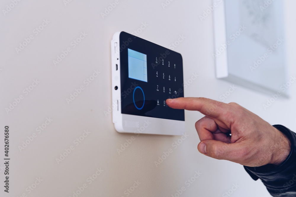 Close up picture on the man's hand unlocking the alarm in the apartment. Home security alarm.