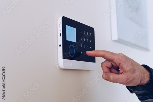 Close up picture on the man\'s hand unlocking the alarm in the apartment. Home security alarm.
