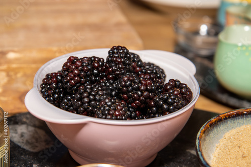 A bowl of blackberries in a pink plastic bowl in a kitchen ready to be cooked
