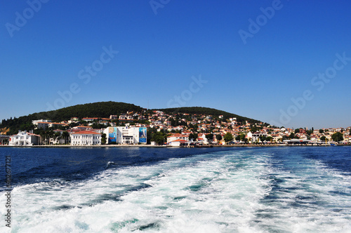 Panoramic views of the sea coast and houses. Calm sea with foam from boat propellers.