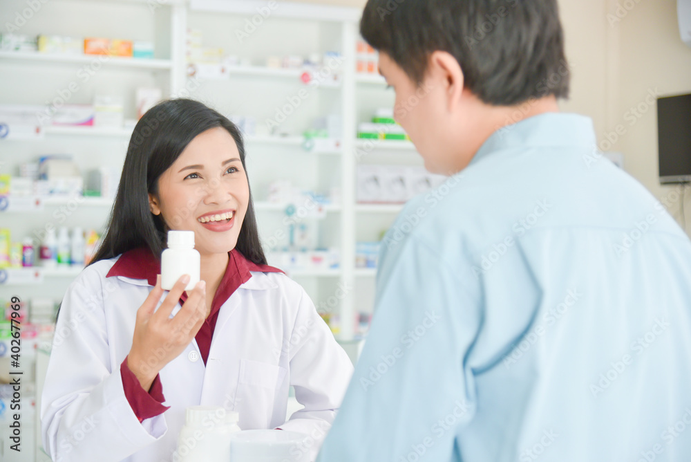 Smiling asian professional young pharmacist showing medicine bottle to customer at drugstore. Smiling asian professional young pharmacist showing medicine bottle to customer at drugstore.