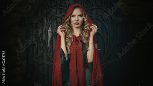 Close up portrait of a beautiful young blonde girl in the medieval green dress with cape in the hood. Amazing model looking at camera fiercely. The legends of Camelot and Lady Guinevere photo