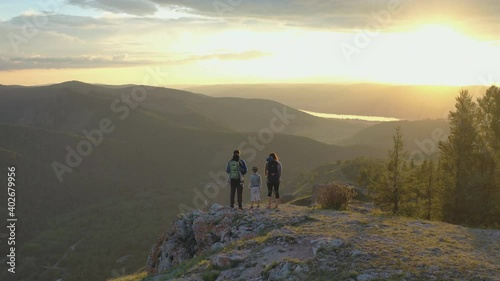 Parents with children at the top of the mountain enjoy the sunset view.