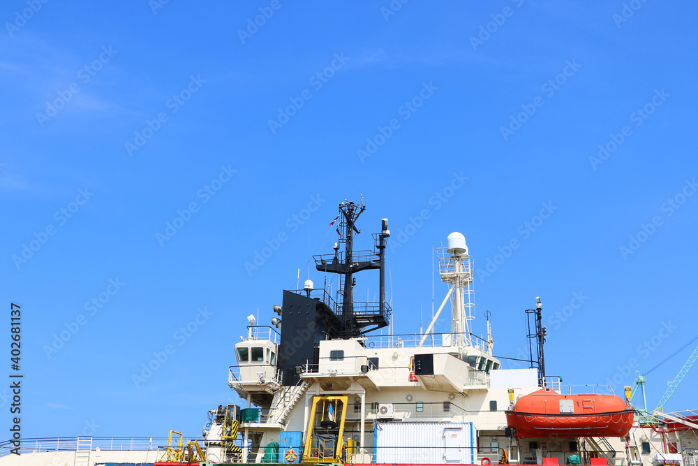 Navigation bridge deck of cargo ship, Cabin bridge deck of tugboat outside view with communication mast and radar on blue sky Navigation bridge deck of cargo ship, Cabin bridge deck of tugboat outside view with communication mast and radar on blue sky