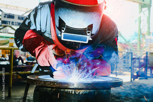worker with Torch head Mig Mag, Operator welding machine metal steel pipe by MIG welding photo