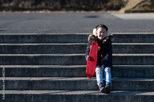 スケートボードを持って階段に座る少女