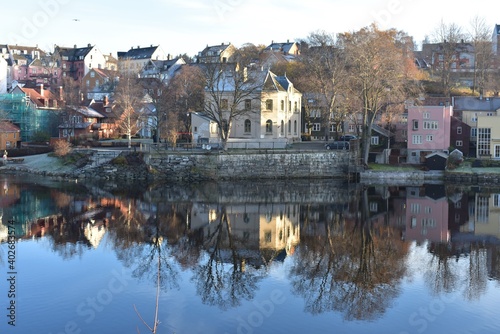 Cityscape of Trondheim city and leafless tree reflection in the water at Nidelva river Norway in early winter. 