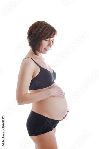 Brunette pregnant woman in black underwear isolated on white background.
