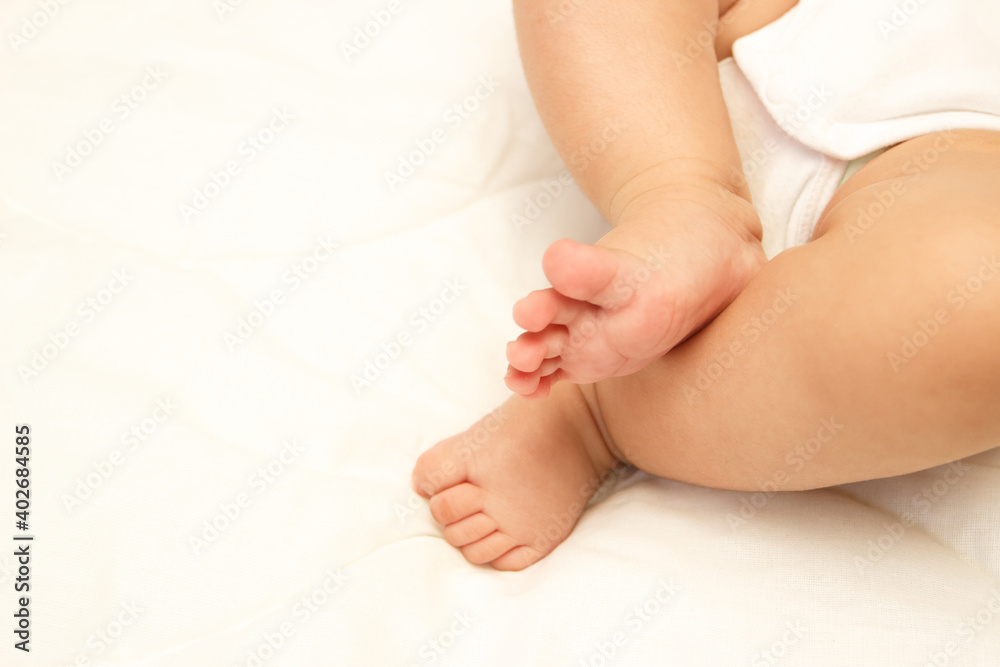 Legs of infant on the white blanket, bedroom, blurred background Legs of infant on the white blanket, bedroom, blurred background