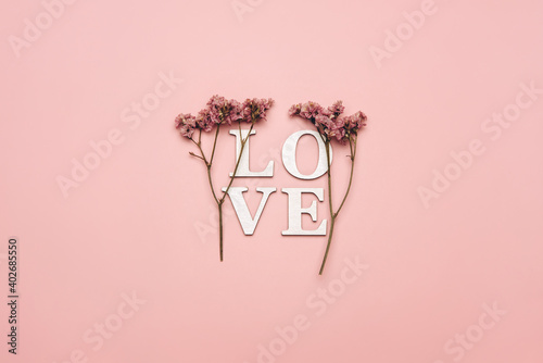 Creative flat lay of word love on soft color  background with natural plants