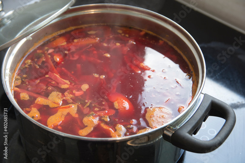 A boiling pot of traditional sour Borscht soup,  one of the most famous dishes of Ukrainian cuisine, made with beetroots as one of the main ingredients, which give the dish its distinctive red color