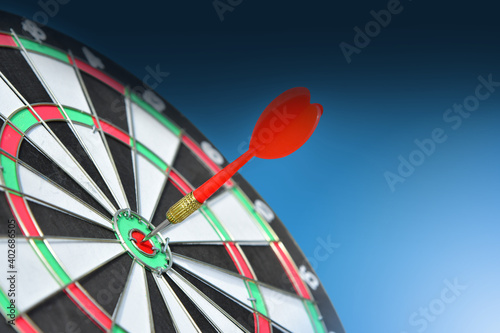 Red Darts hitting on Dartboard and hand pointing for the game focuses on success, planning to be smart concept, on blue sky background.