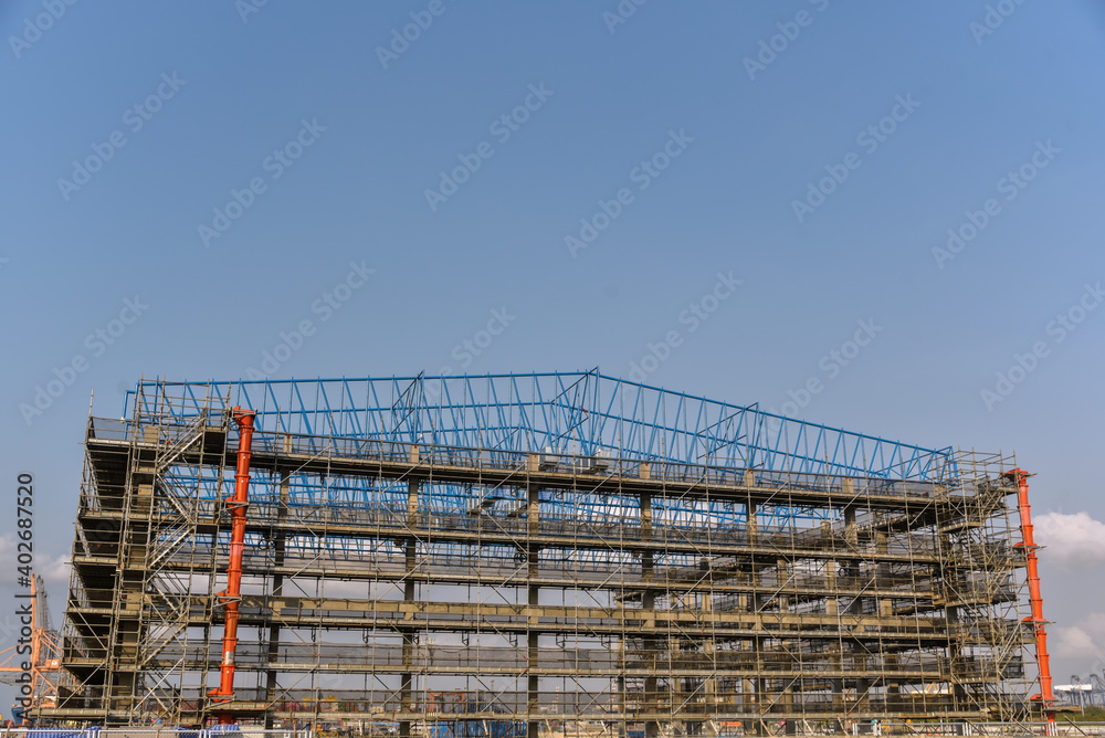 Steel structure of factory, wearhouse in construction site with scaffolding.