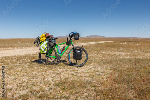 Fototapeta Naklejka Na Ścianę i Meble -  Touring bike full loaded standing on a dirty road. tourist bike with bags. Mongolian steppe.