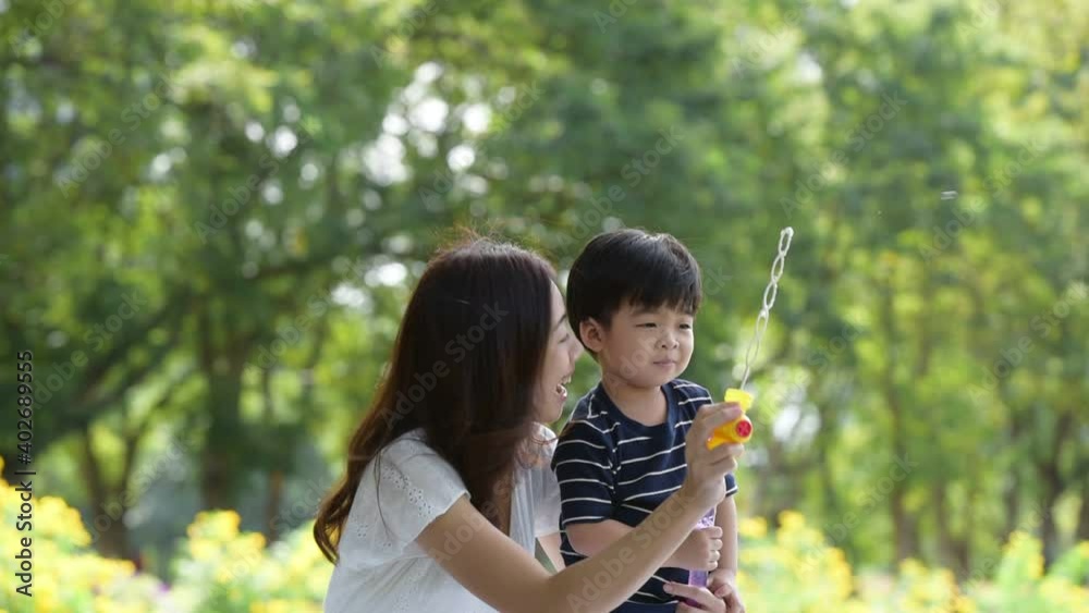 Happy Asian family having fun mother and her son playing with soap bubbles in the park together Happy Asian family having fun mother and her son playing with soap bubbles in the park together
