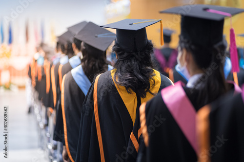Rearview of the university graduates line up for degree award in university graduation ceremony. The university graduates are gathering in the university graduation ceremony. Crowd of the graduates.