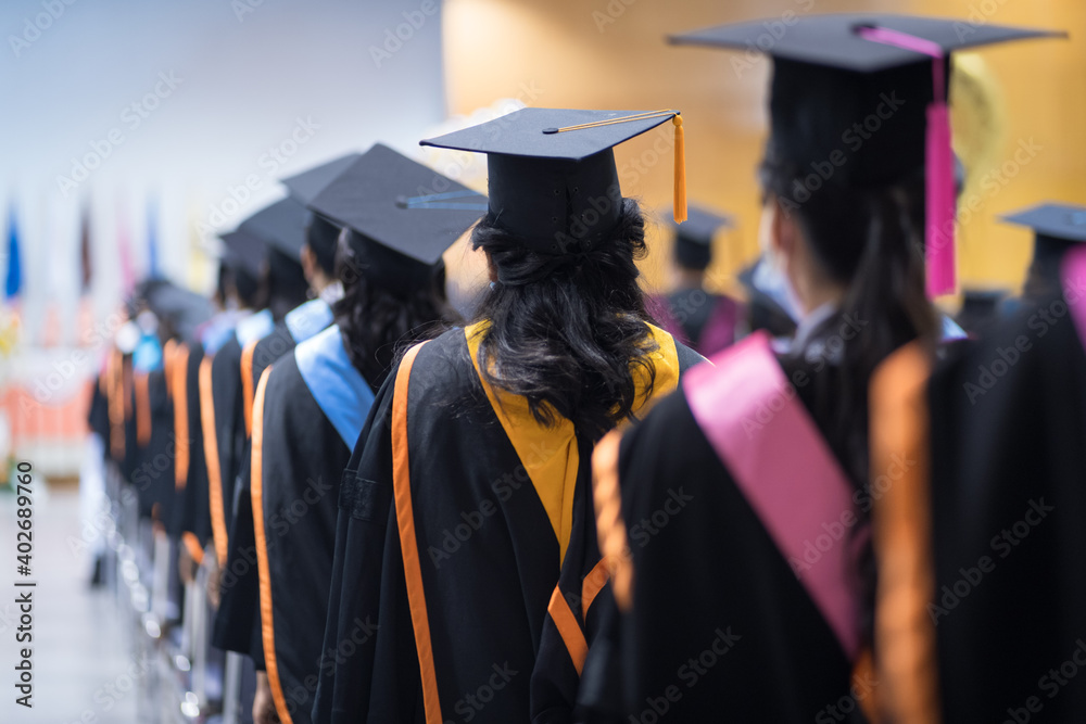 Rearview of the university graduates line up for degree award in university graduation ceremony. The university graduates are gathering in the university graduation ceremony. Crowd of the graduates.