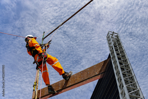 Safety Sprinkle of high, Construction wearing safety harness and Safety line working on a Metal indutry structure installed scaffolding.