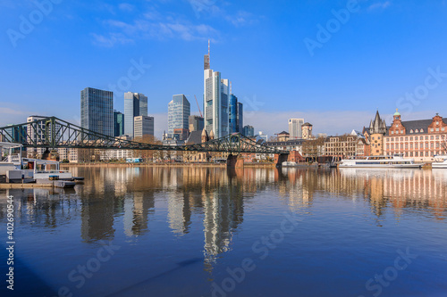 Frankfurt skyline in sunshine. Commercial buildings and bridge over the river Main with reflections. Ships at the moorings and historic buildings