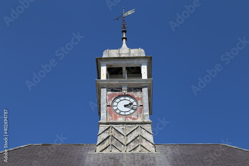 A close up view of the dilapidated clock tower with weather vane on a Town Hall building in Wales. photo